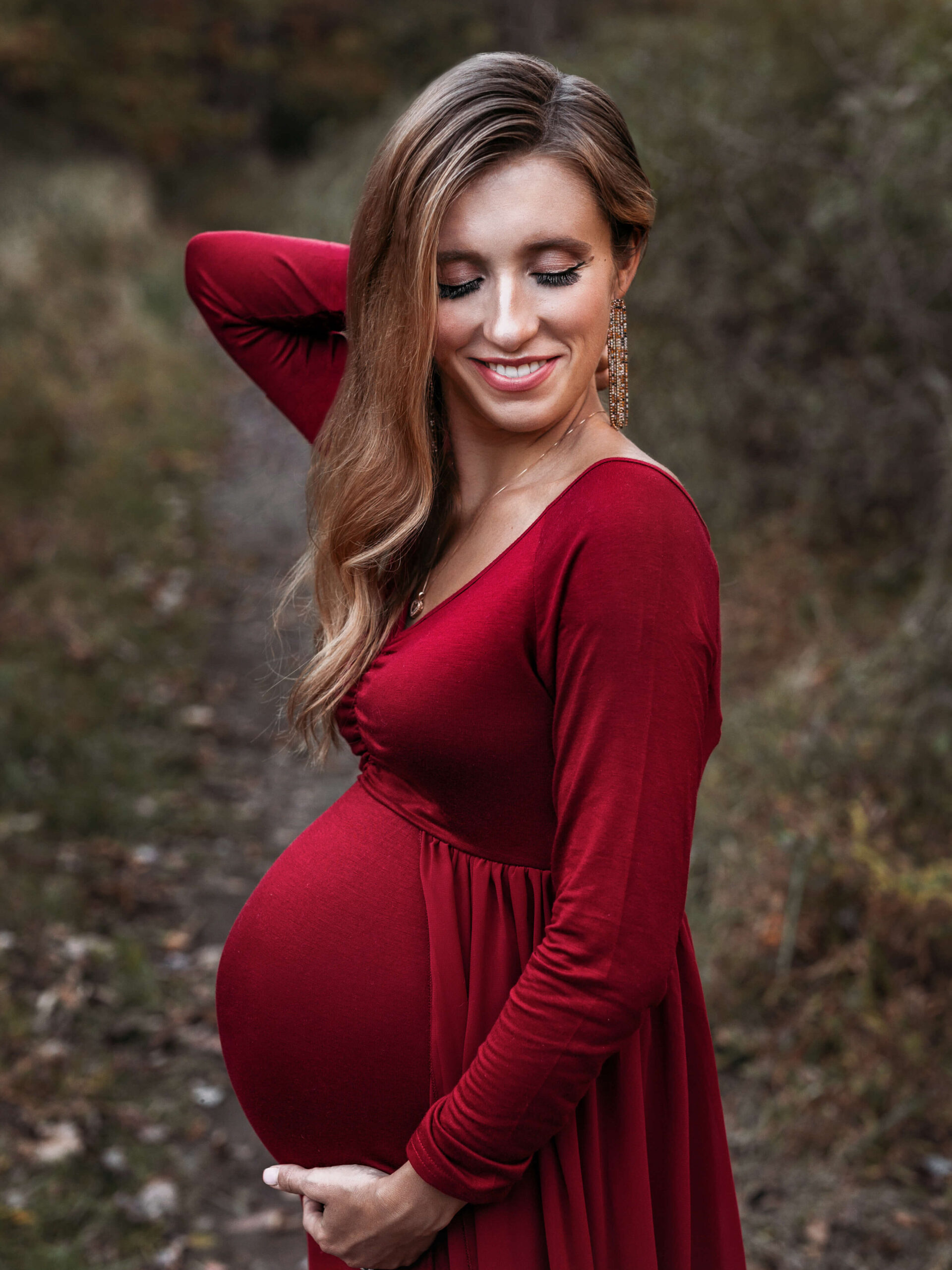  northern virginia pregnancy an maternity photographer capturing a pregnant woman posing in a red maternity gown in Great Falls Virginia a an outdoor park in the fall at dusk