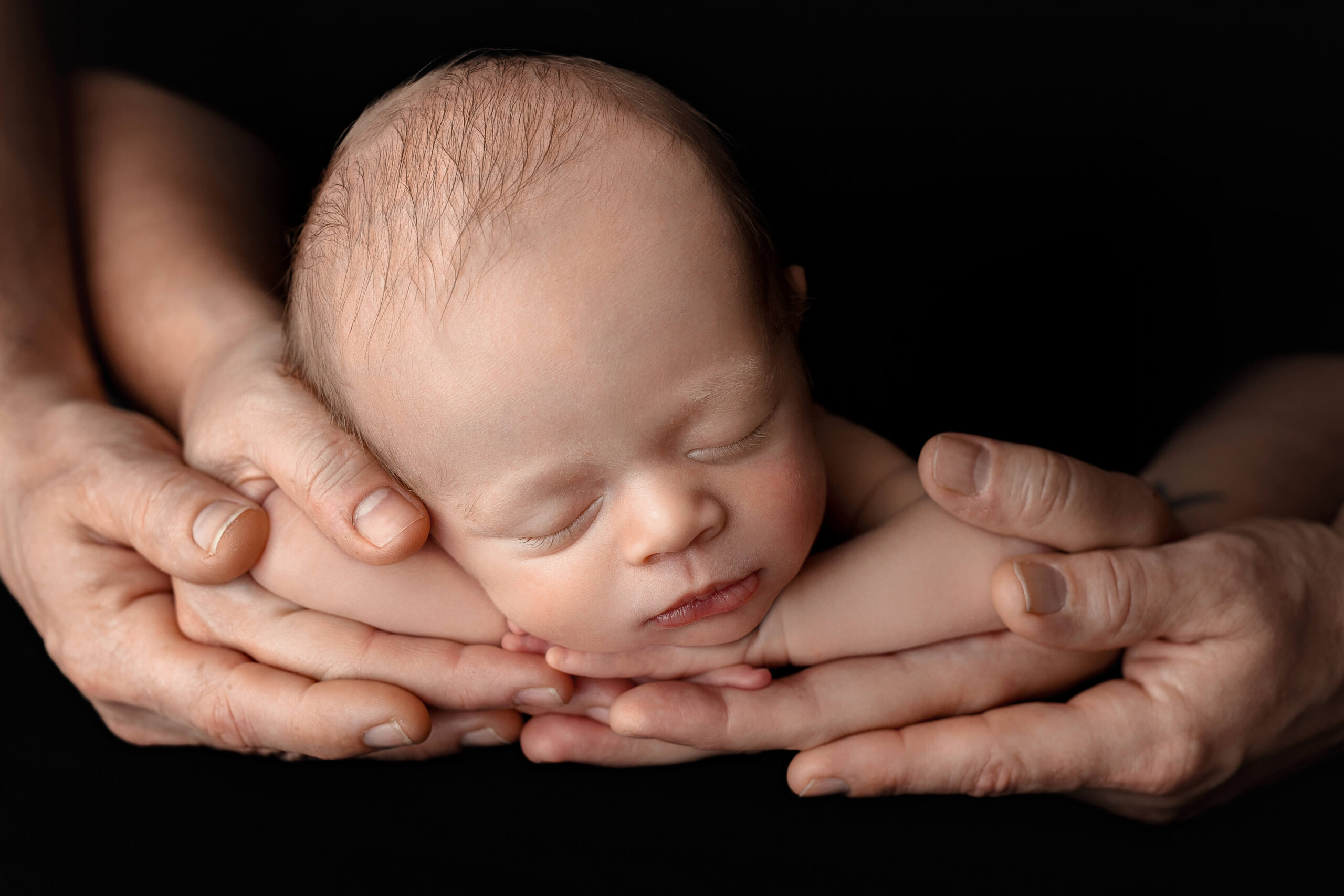 Newborn baby in his fathers hands at his newborn photography session