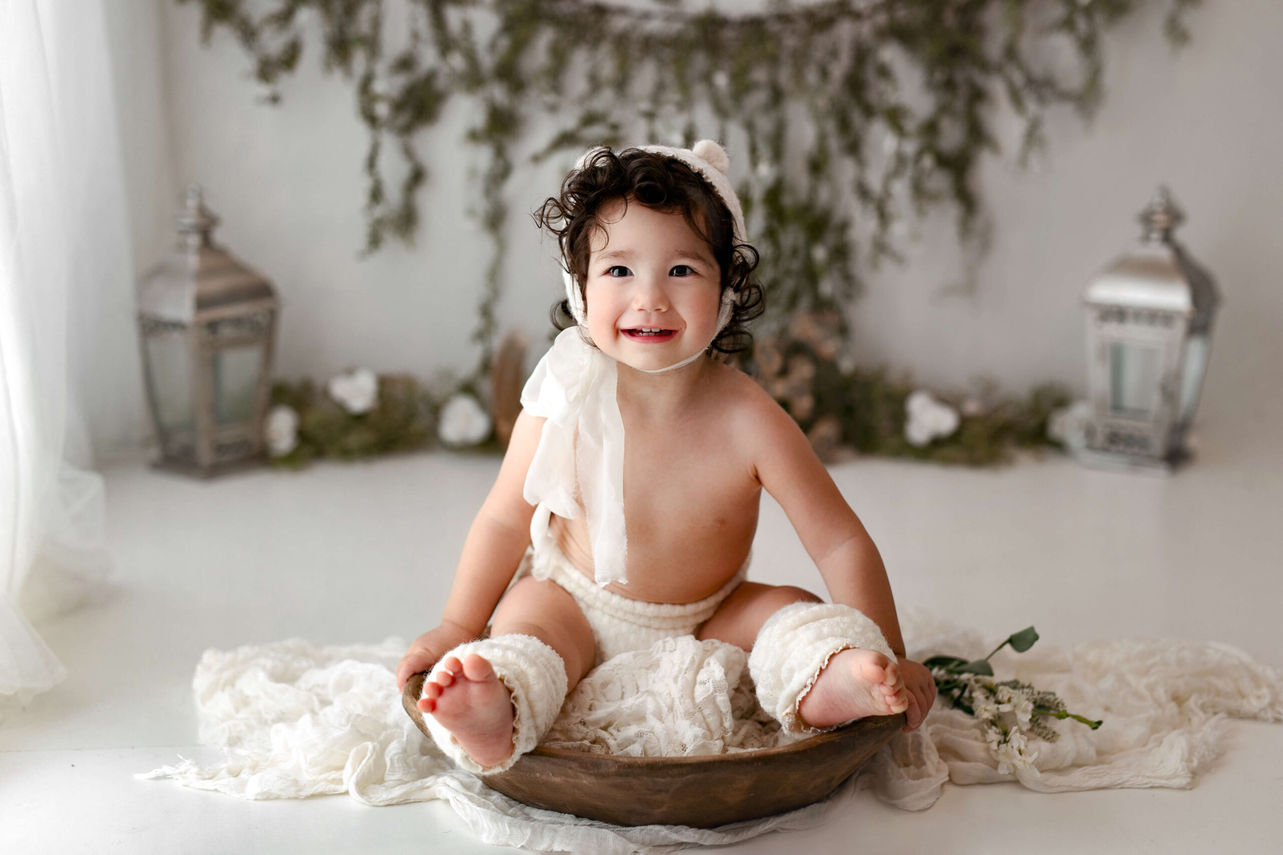 Milestone Photo of a 9 month old baby girl sitting in a bowl with a bear hat on at her in-studio toddler photography session