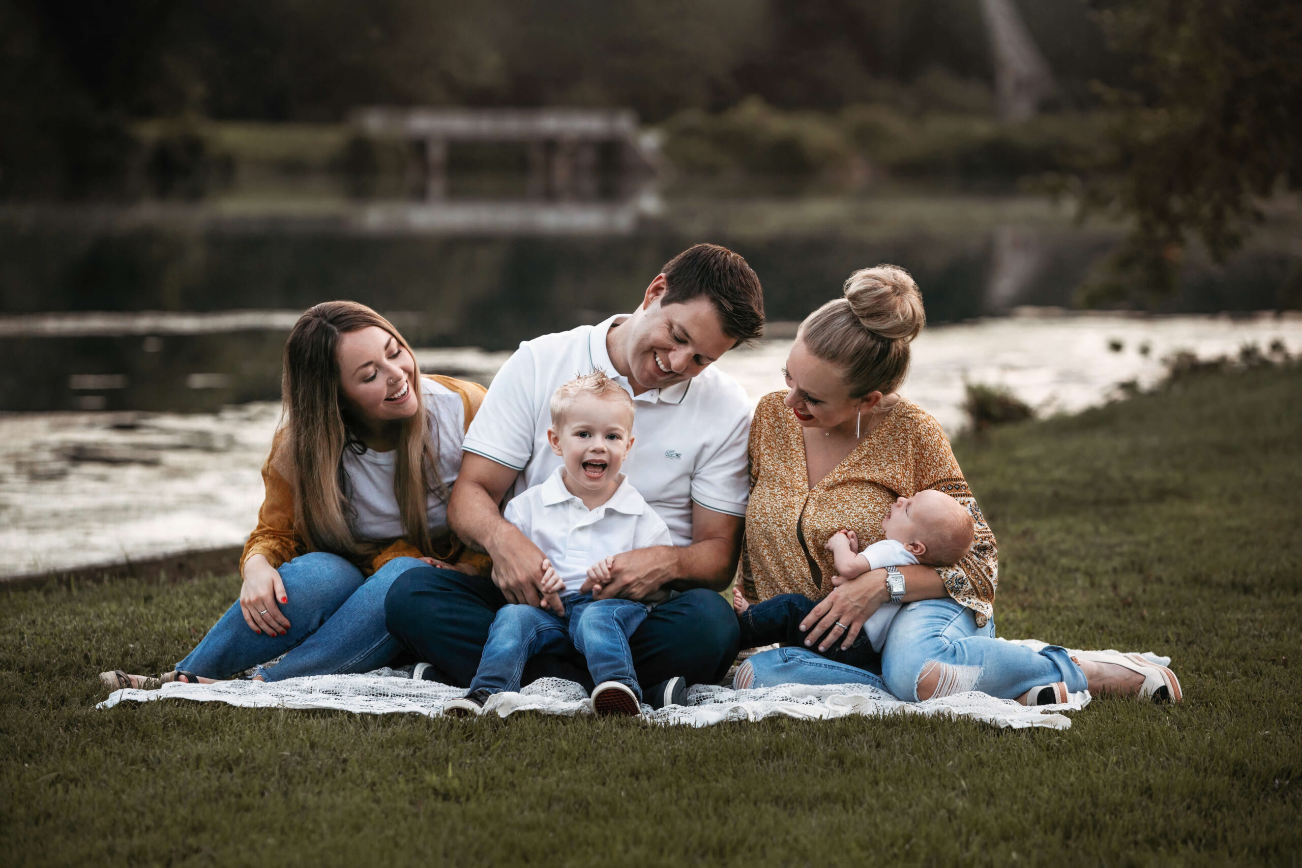 a family sitting on a blanket at golden hour in the summer at their outdoor family photography session at the best time to take photos outside