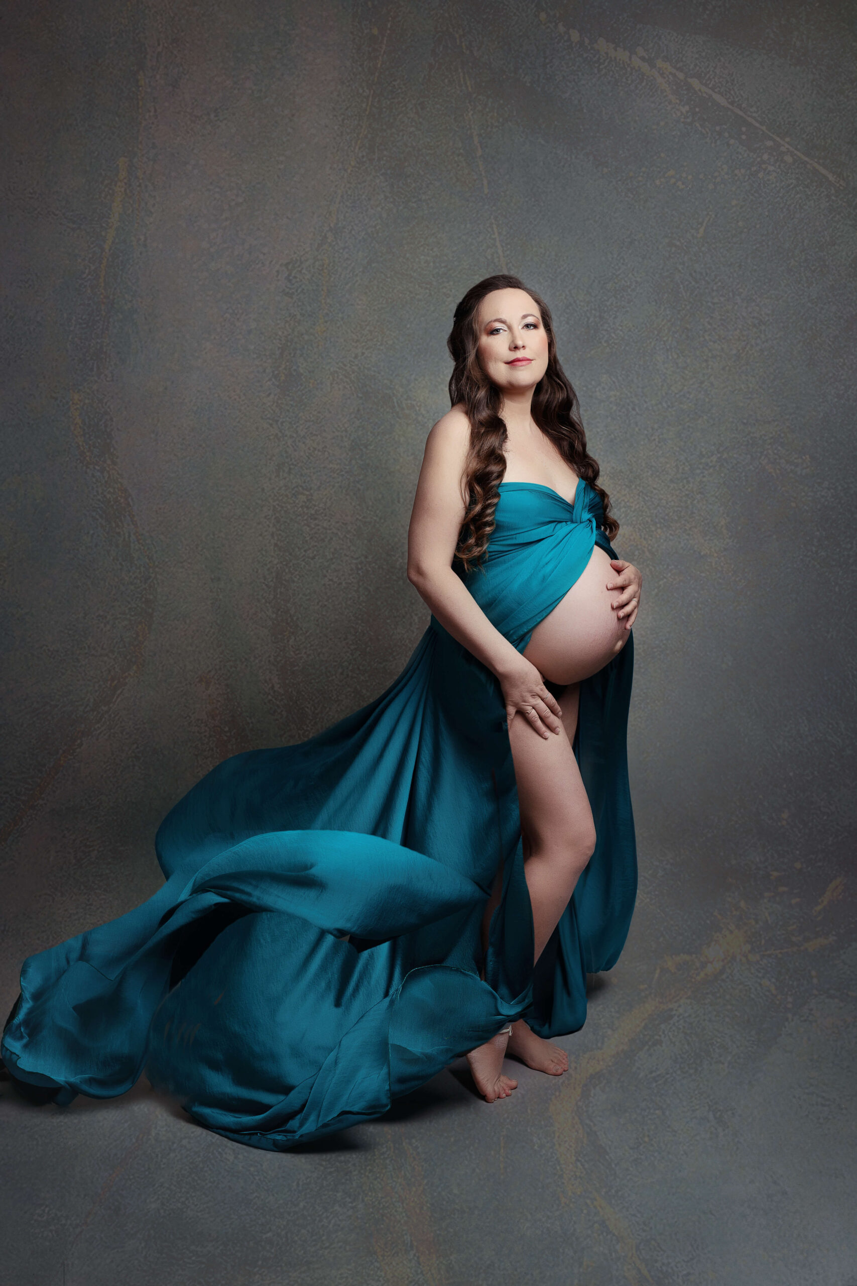 pregnant woman in a blue maternity gown at a studio creative maternity photoshoot