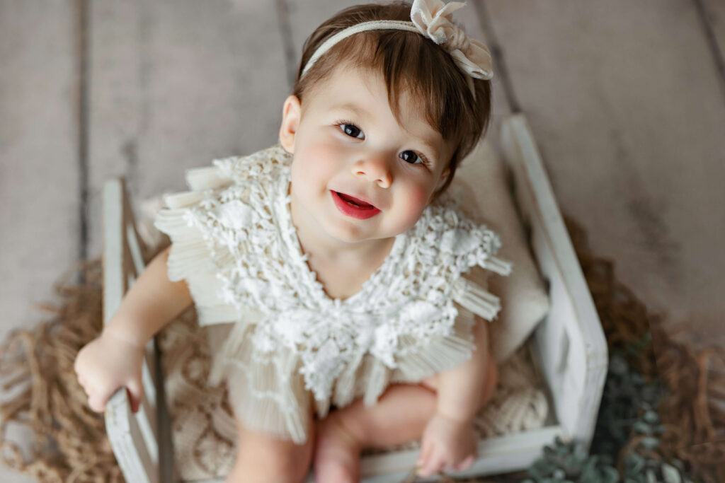 one year old toddler sitting on a white bed at her First Birthday Photo Shoot Northern VA