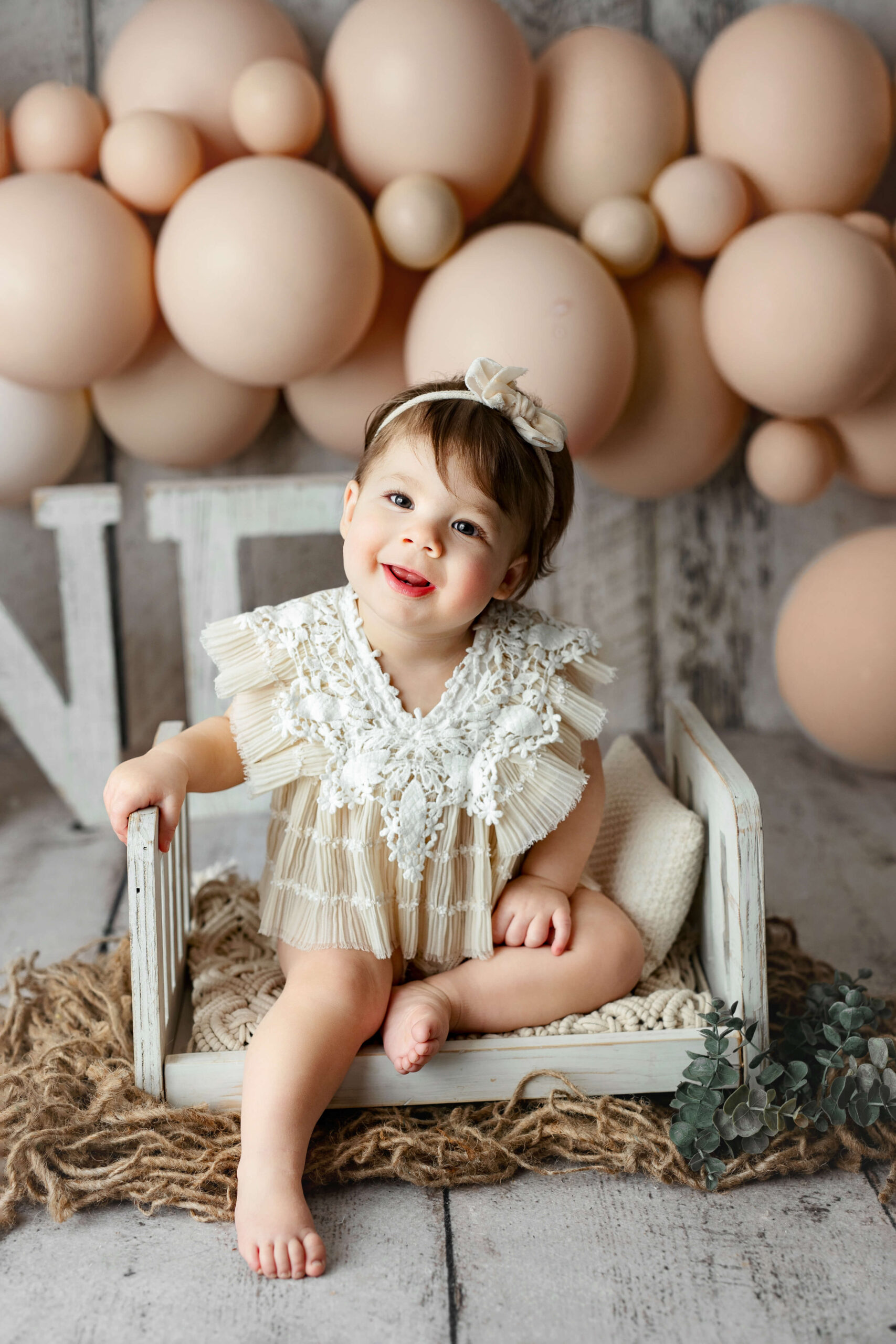one year old toddler sitting on a white wooden bed at her First Birthday Photo Shoot Northern VA