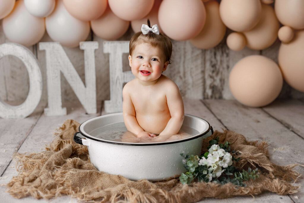 little girl with a bow in a bath tub in a cake smash session