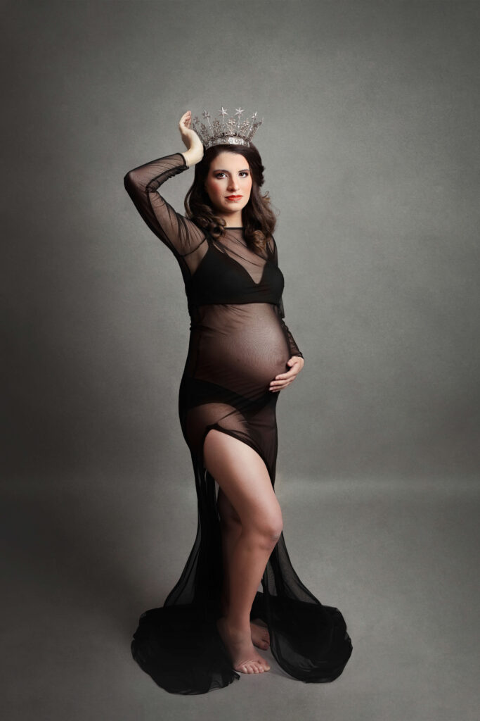 pregnant mother wearing a black maternity dress  with a crown in her in studio maternity session in va by Maternity Photographer Tysons Corner VA