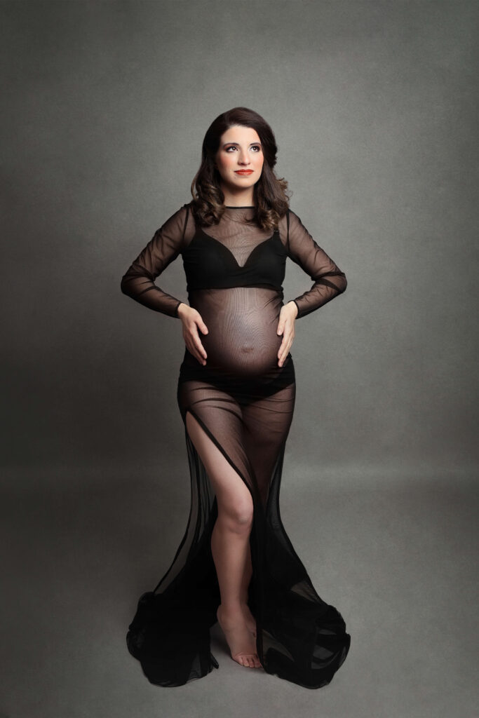 pregnant mother wearing a black maternity dress with her hands on her hips in her in studio maternity session in va by Maternity Photographer Tysons Corner VA