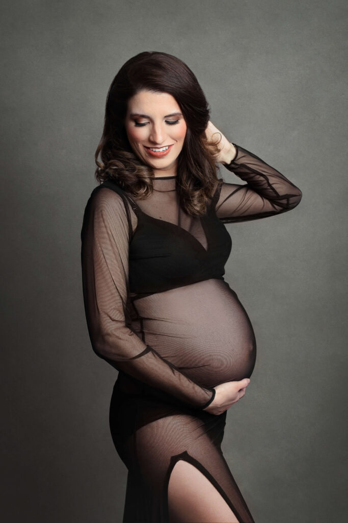 pregnant mother wearing a black see through maternity dress in her in studio maternity session in va by Maternity Photographer Tysons Corner VA