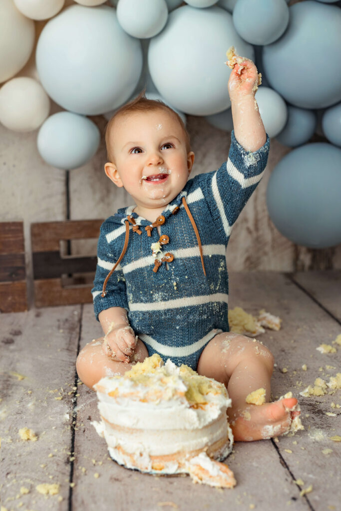one year old playing with cake at his first birthday session
