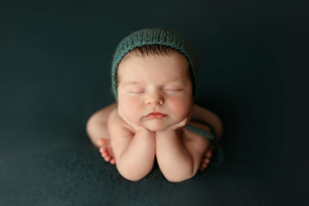 newborn in froggy pose on a teal backdrop taken by a Northern Virginia Newborn Photographer