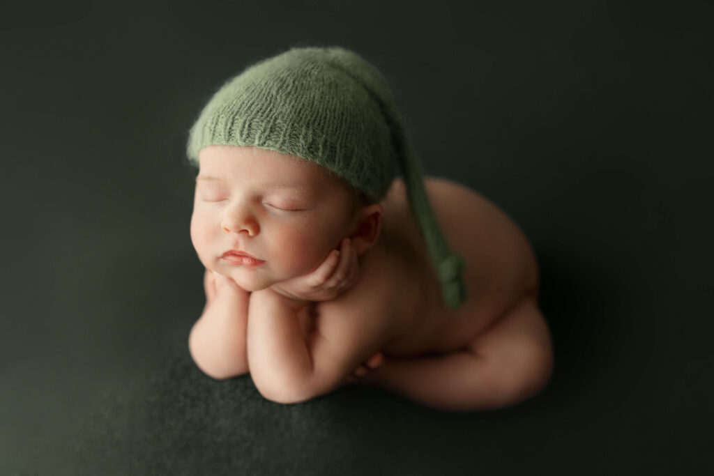 newborn in froggy pose on a green backdrop taken by a Northern Virginia Newborn Photographer