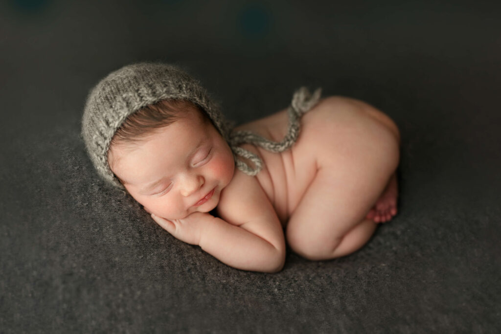 newborn in bum up pose on a grey backdrop taken by a Northern Virginia Newborn Photographer