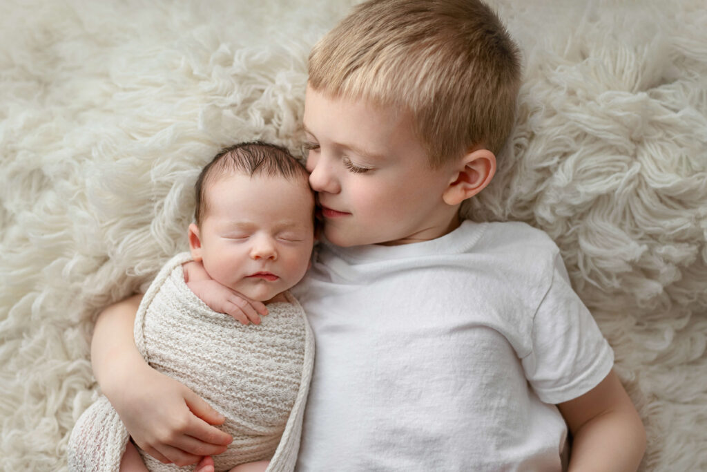 newborn being held and kissed by his big brother taken by a Northern Virginia Newborn Photographer