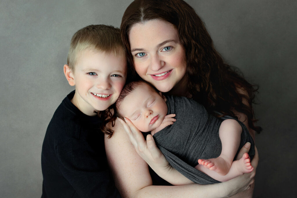 mom holding her newborn with her older son taken by a Northern Virginia Newborn Photographer