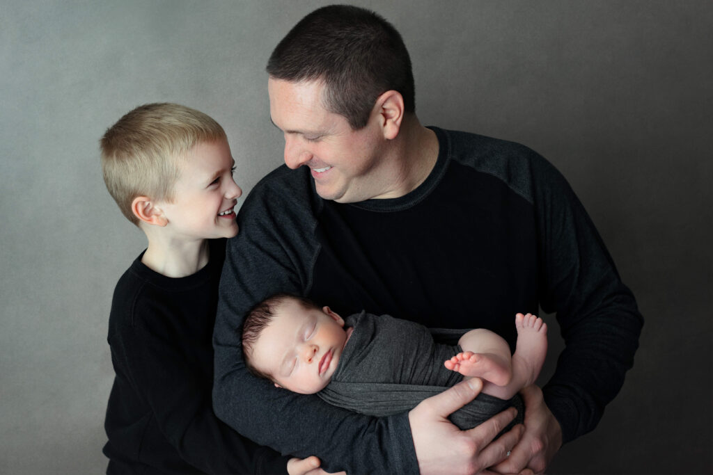 dad holding his newborn with her older son taken by a Northern Virginia Newborn Photographer