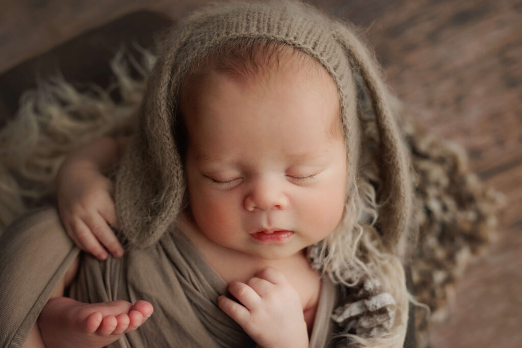 newborn baby on a wooden bowl with a bunny bonnet